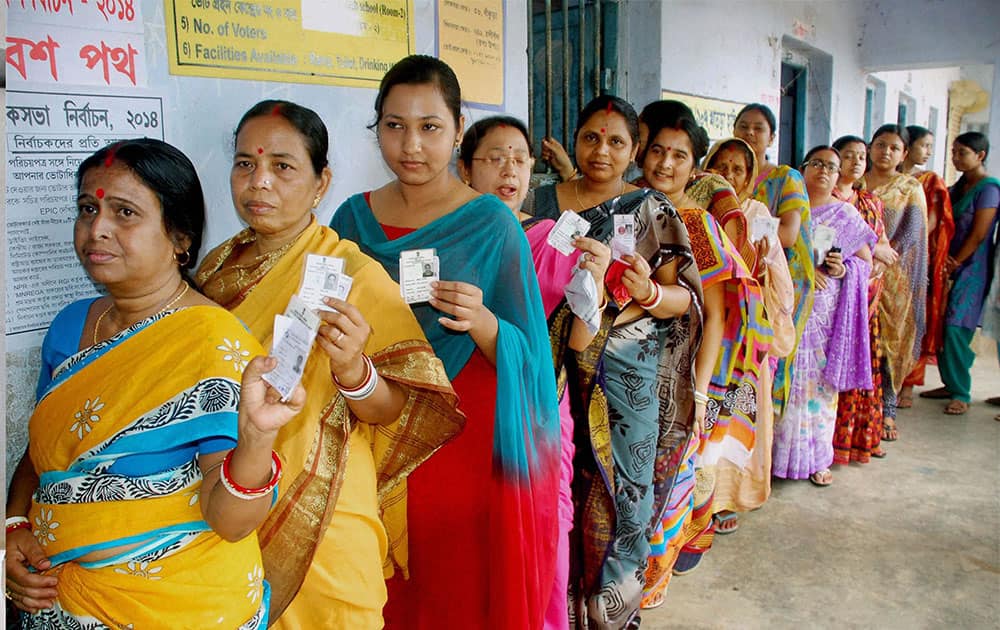 Women voters showing their voter identity cards as they wait in a queue to cast their vote at a polling booth at Bankura district in West Bengal.