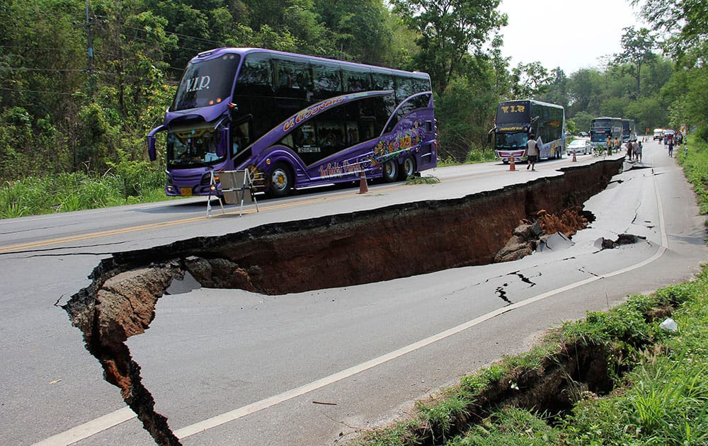 Buses carrying tourists slowly cruise through a cracked road after an earthquake in Chiang Rai province, northern Thailand.