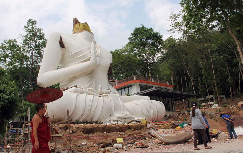 A Buddhist monk and villagers examine a damaged Buddha statue following an earthquake in Chiang Rai province, northern Thailand.