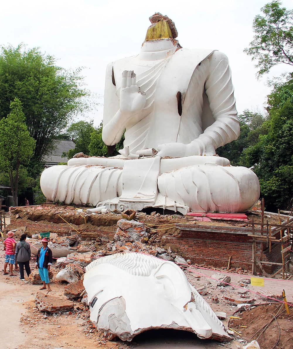 Thai villagers examine a damaged Buddha statue following an earthquake in Chiang Rai province, northern Thailand.