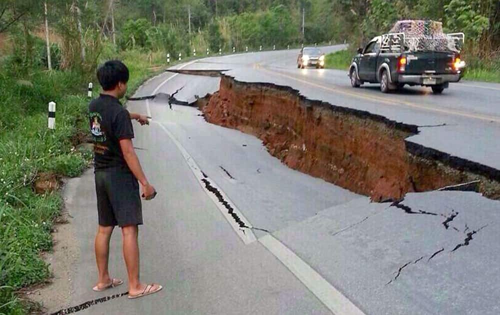 A man points a big crack on a damaged road following a strong earthquake in Phan district of Chiang Rai province, northern Thailand.