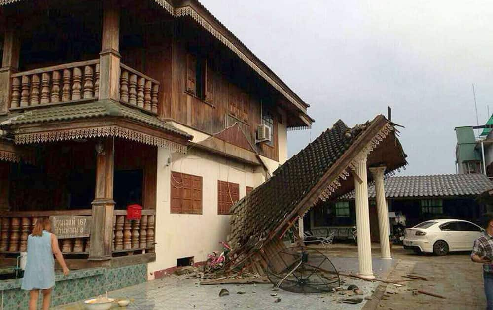 A woman looks at a partly damaged house following an earthquake in Chiang Rai province, northern Thailand.