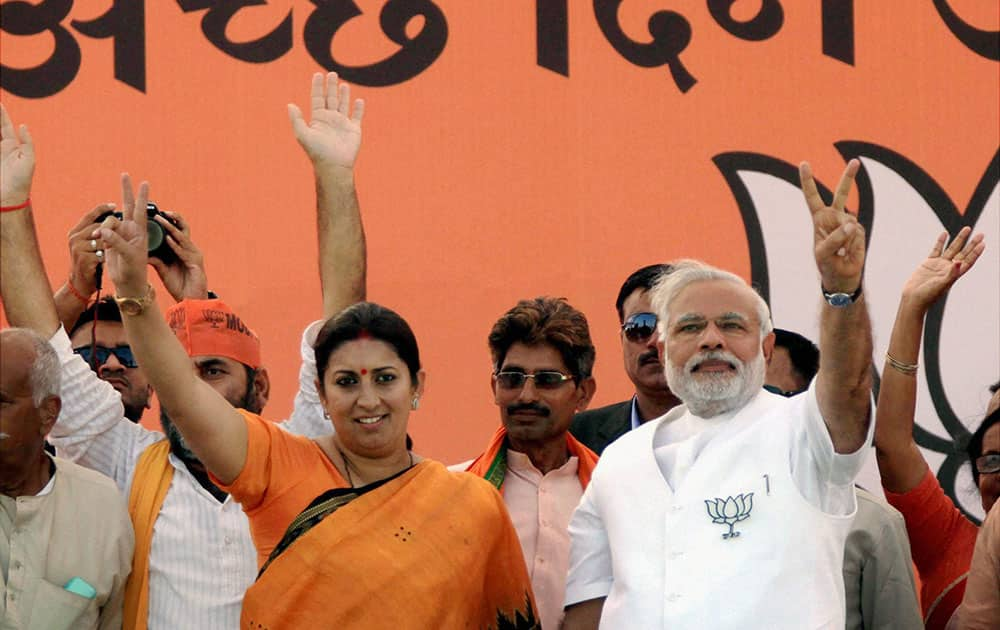 BJP PM candidate Narendra Modi with party candidate Smriti Irani flashes victory sign during an election rally in Amethi.