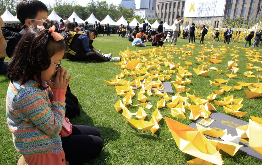 A girl prays in front of paper ships bearing messages for the victims of the sunken ferry Sewol at a group memorial altar in Seoul, South Korea.