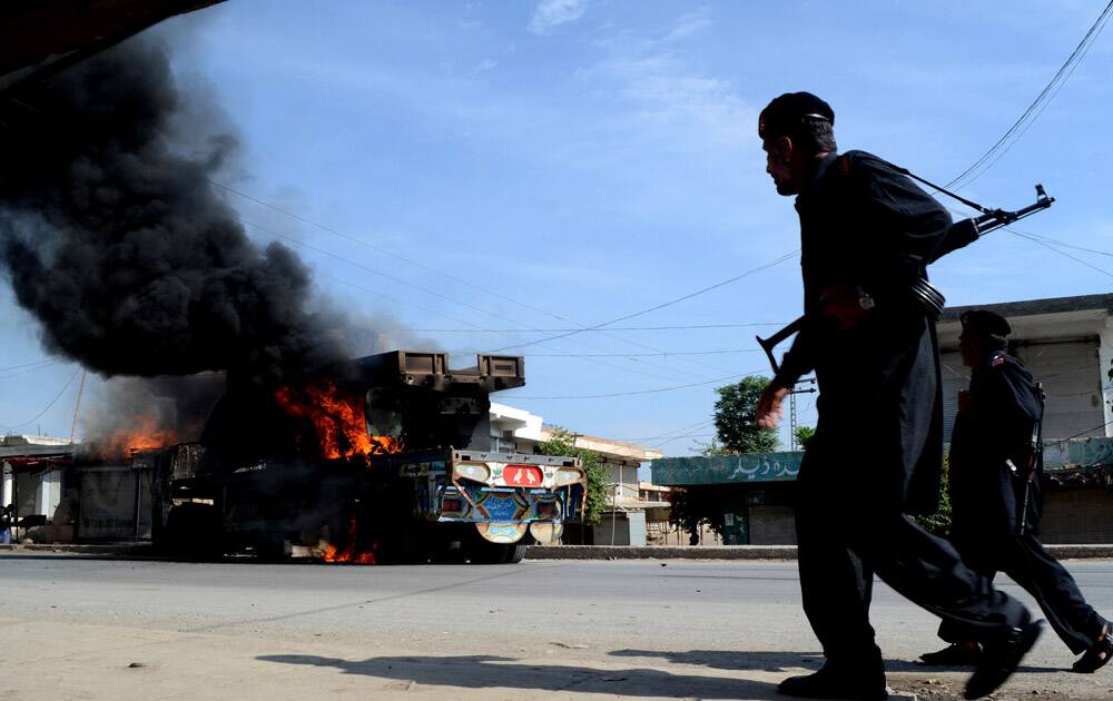 Pakistani para military troops walk inspect burning NATO trucks in the Pakistani tribal area of Jamrud near Peshawar.