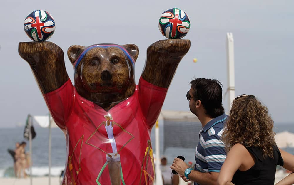 A couple look at a statue of a bear that forms part of the United Buddy Bears exhibit, during a protest against the money spent on preparations for the 2014 Wcup, on the Leme beach seafront in Rio de Janeiro, Brazil.