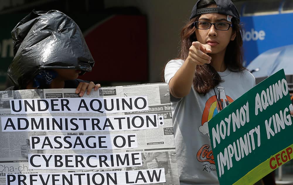 A protester, with a head covered in a black plastic bags to symbolize their indignation allegedly for lack of justice, displays placards during a rally near the Presidential Palace in Manila, Philippines.