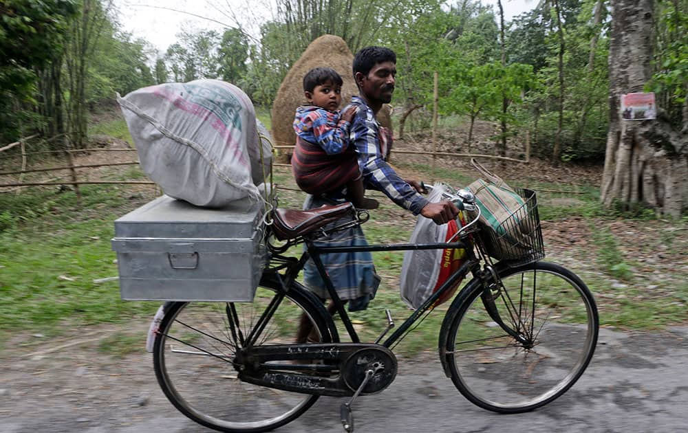 A villager carries a child and pushes a bicycle with his belongings to flee ethnic violence in Narayanguri village, in the northeastern Indian state of Assam.