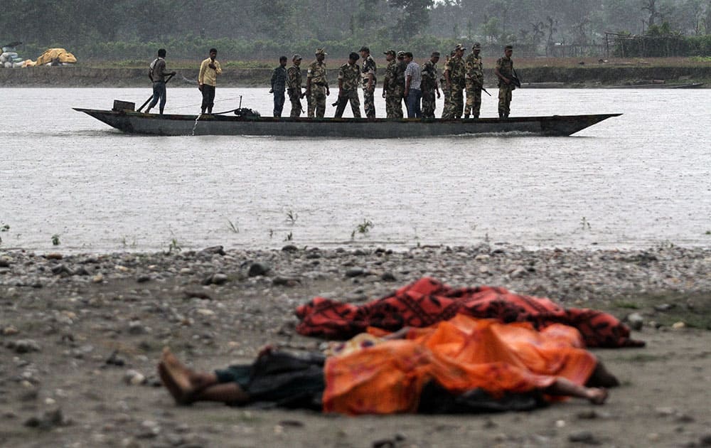 Bodies of victims killed in ethnic violence lie covered on the banks of the River Beki, as security officers patrol the area on a boat at Khagrabari village, in the northeastern Indian state of Assam.