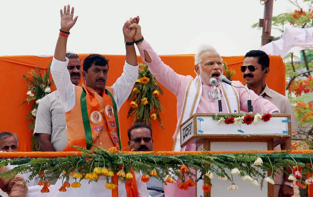 BJP PM candidate Narendra Modi addresses an election campaign rally for party candidate Sharad Tripathi (L) in Sant Kabir Nagar.