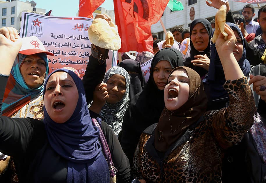 Palestinian labors hold loaves of bread while chanting slogans during a march for the International Labor Day at the Palestine square in Gaza City, northern Gaza Strip.