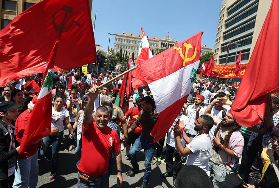 Supporters of the Lebanese Communist Party dance as they hold Lebanese and Communist Party flags during a demonstration to mark Labor Day in Beirut, Lebanon.