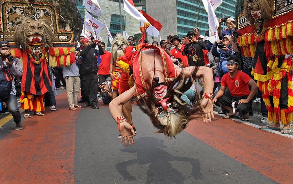 A masked dancer somersaults as he performs during a May Day rally in Jakarta, Indonesia.