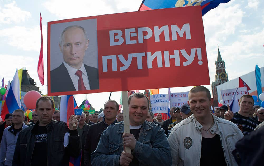 People holding Russian flags and posters march during the May Day celebration at the Red Square in Moscow, Russia.