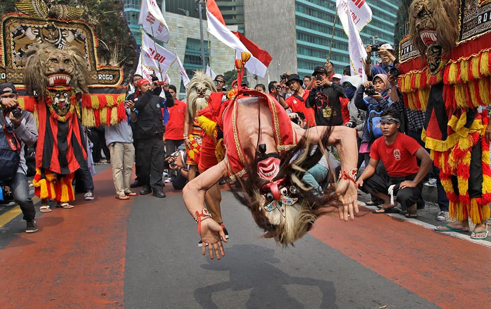 A masked dancer somersaults as he performs during a May Day rally in Jakarta, Indonesia.