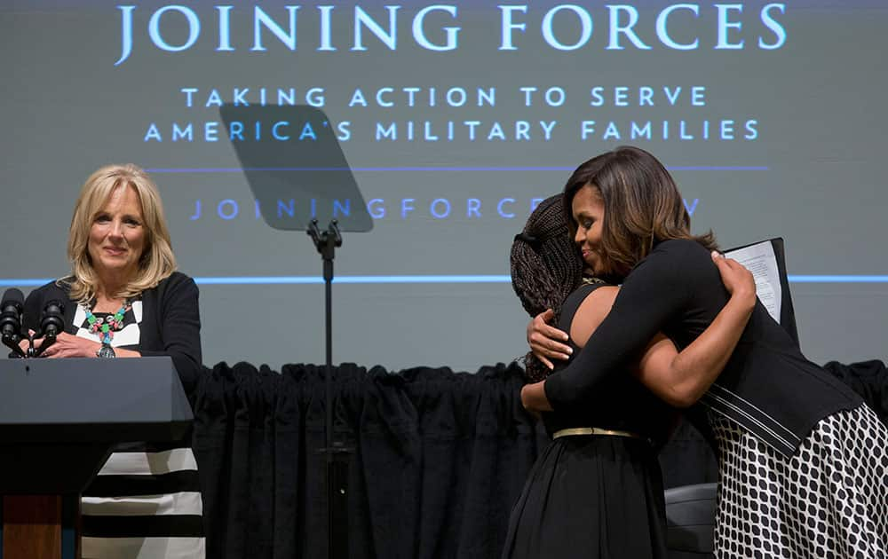 First lady Michelle Obama hugs Chrissandra Jackson accompanied by Dr. Jill Biden, at the third anniversary of Joining Forces, at the American Red Cross Hall of Service in Washington. Mrs. Obama announced pledges in excess of $150 million from foundations and corporations to help veterans and their families get the services they need in the places where they live as the country adjusts to a postwar footing. Jackson is a daughter of a military family.