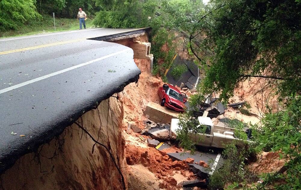 Vehicles rest at the bottom of a ravine after the Scenic Highway collapsed near Pensacola, Fla. Heavy rains and flooding have left people stranded in houses and cars in the Florida Panhandle and along the Alabama coast. 