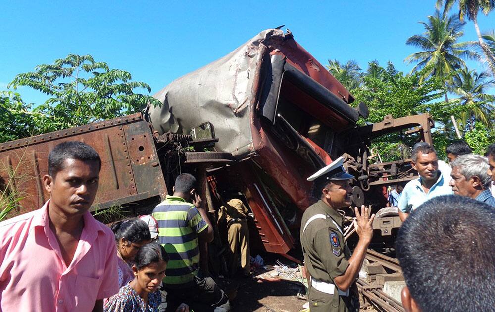 Sri Lankans stand near mangled coaches after two trains collided at a railroad station in Pothuhera, about 90 kilometers (56 miles) northeast of Colombo, Sri Lanka.