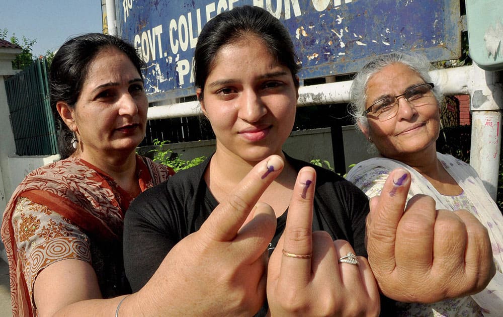 A girl, her mother and grandmother show their inked fingers after casting their votes at a polling station in Patiala.