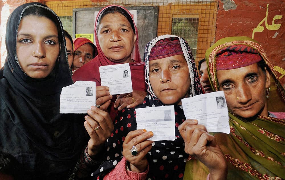 Kashmiri women show their voter cards as they stand in a queue to cast their votes at a polling station in Ganderbal.