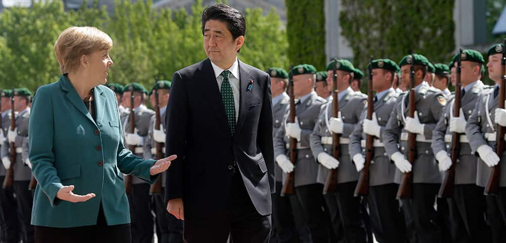 German Chancellor Angela Merkel, left, welcomes Prime Minister of Japan Shinzo Abe, right, with military honors at the chancellery in Berlin, Germany.