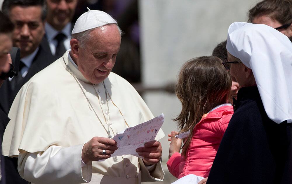 Pope Francis reads a message he was given by a child at the end of his weekly general audience, at the Vatican.