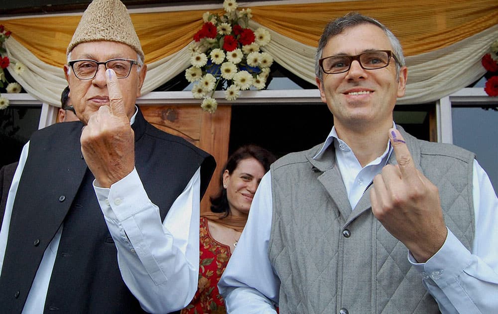 National Conference candidate Farooq Abdullah and his son and J&K Chief Minister Omar Abdullah show their inked fingers after casting votes for Lok Sabha elections, at a polling centre in Srinagar.