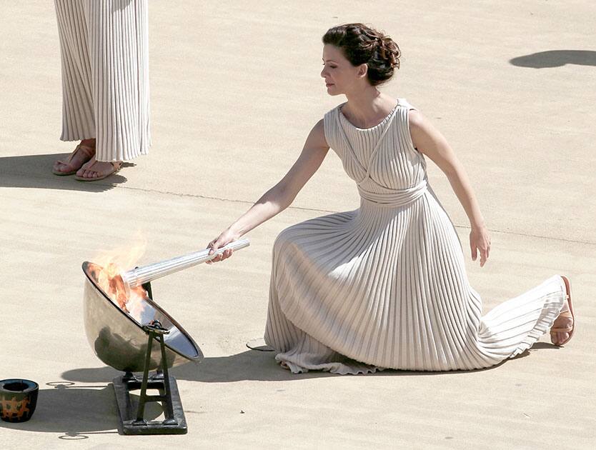 Greek actress Katerina Lehou, playing the role of high priestess, lights the torch with the Olympic Flame during a handover ceremony at Panathenaean stadium in Athens.