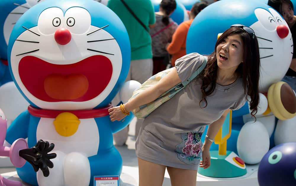 A woman poses next to a model of Doraemon, one of Japan`s most popular animation characters, during the `100 Doraemon Secret Gadgets Expo` held outside a shopping mall in Beijing, China.