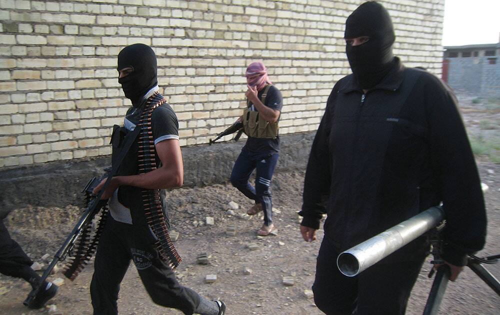 Masked anti-government gunmen move with their weapons as they patrol in Fallujah, Iraq. 