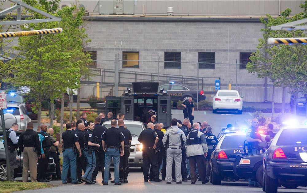 Police officers from Cobb County,Marietta and Kennesaw departments stage near the entrance of the Federal Express Ground building in Kennesaw, Ga., after a man opened fire inside the building before turning the gun on himself.