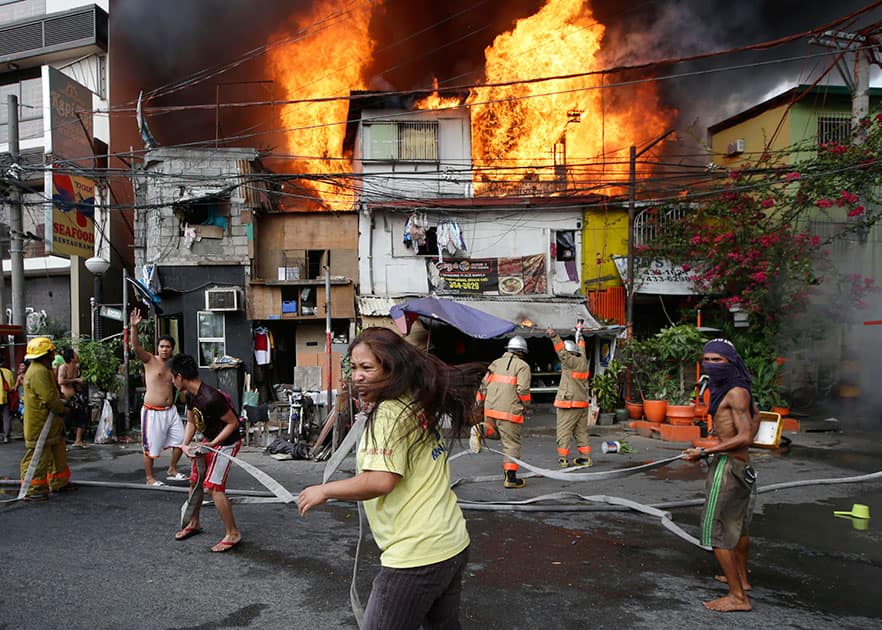 Residents help firemen in putting out fire that engulfs a poor neighborhood, in Manila, Philippines. Authorities said three people died in the hour-long fire that razed more than a dozen homes and displaced several families.