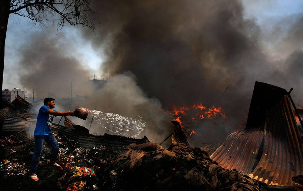 An Indian throws a bucket of water to salvage goods from a warehouse storing leftover cloth strips in New Delhi.