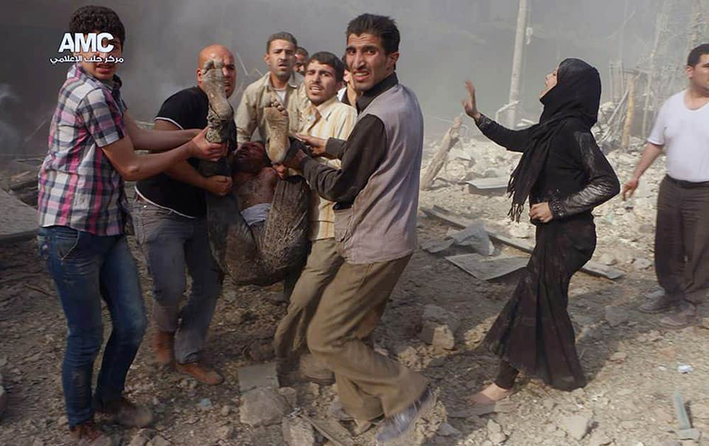 This photo provided by the anti-government activist group Aleppo Media Center (AMC), which has been authenticated based on its contents and other AP reporting, shows Syrian men carrying a wounded victim from the scene after a government airstrike in Aleppo, Syria.