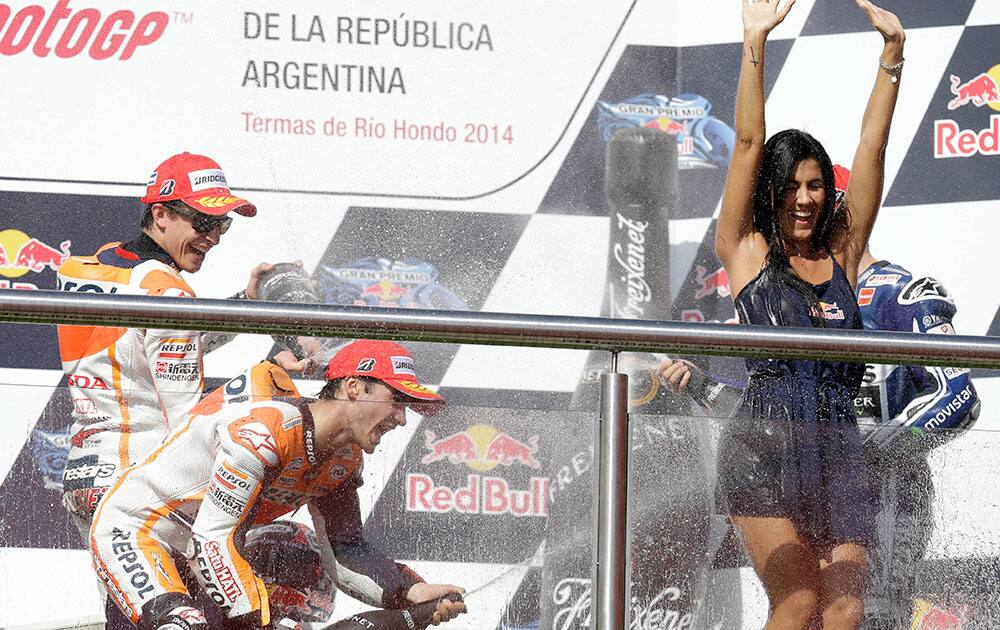 MotoGP rider Spaniard Marc Marquez, center, celebrates his victory on the podium of Argentina`s Motorcycle Grand Prix by spraying sparkling wine on a promotions model, together with second-placed winner Dani Pedrosa, also from Spain, at the Termas de Rio Hondo circuit, Argentina.