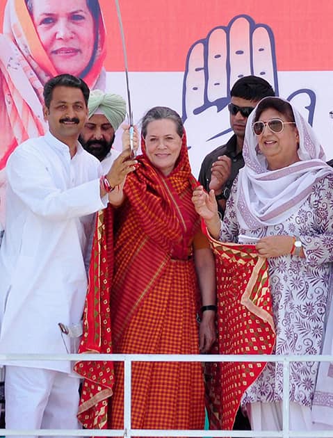 Congress President Sonia Gandhi is presented a sword by party candidate Vijay Inder Singla as party leader Rajinder Kaur Bhattal and others look on during an election rally in Barnala.