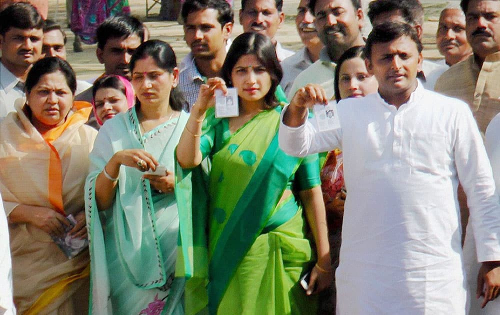 Uttar Pradesh Chief Minister Akhilesh Yadav with his wife Dimple Yadav and other family members show their identity cards after casting votes at a polling booth in Saifai, Etawah.