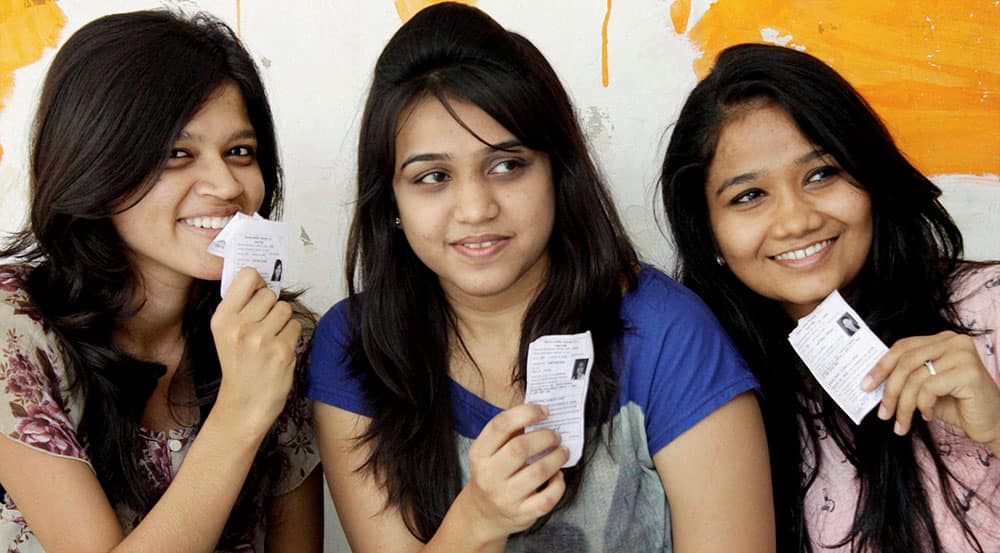 First time voters show their identity cards as they wait to cast their votes at a polling booth in Mumbai.