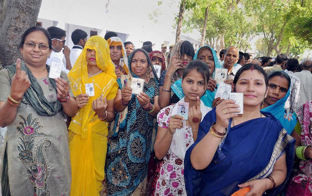 Woman voters show their identity cards after cast their votes at a polling station in Mathura.