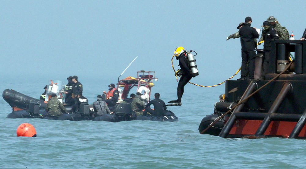 A diver jumps into the sea to look for people believed to have been trapped in the sunken Sewol ferry near buoys which were installed to mark the vessel in the water off the southern coast near Jindo Korea.