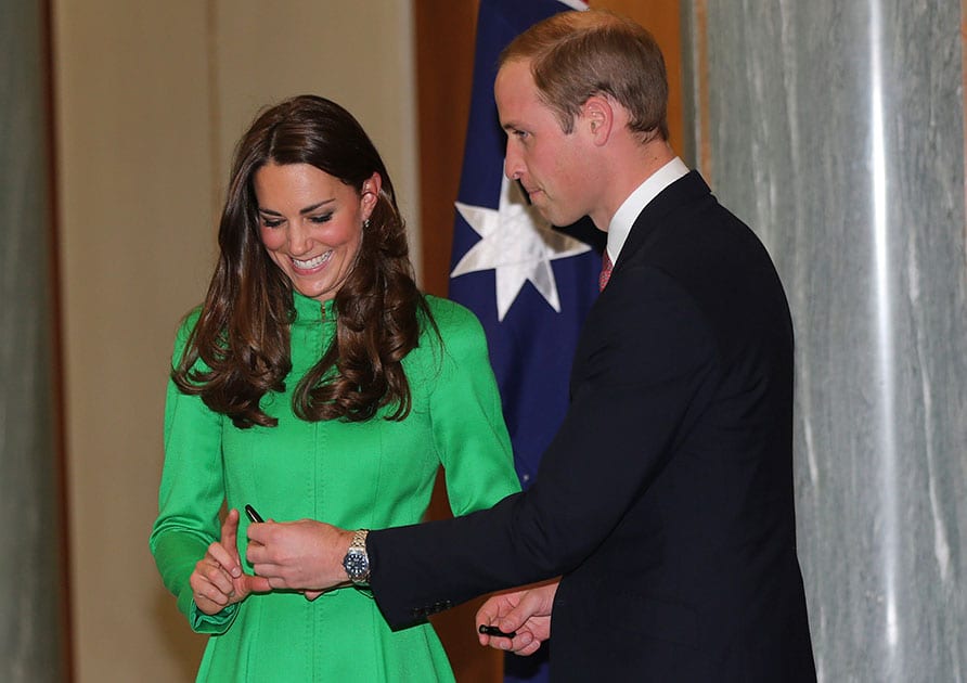 Britain`s Prince William hands his wife Kate, the Duchess of Cambridge a pen to sign the visitors book at a reception hosted at Australia`s Parliament House in Canberra, Australia.