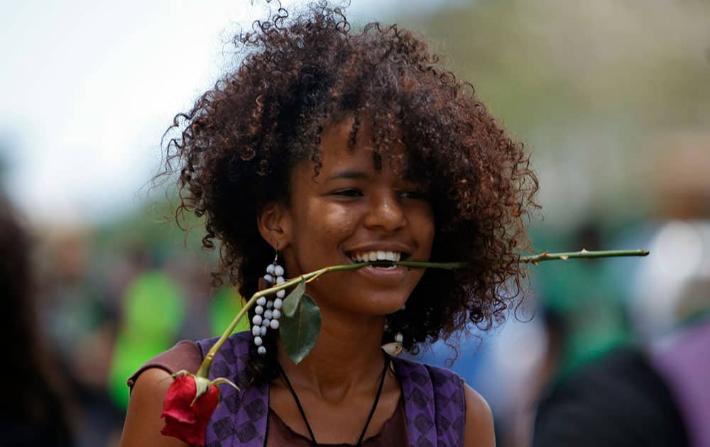 A student carries a flower in her mouth during a protest against a tuition increase outside the University of Puerto Rico in San Juan, Puerto Rico.