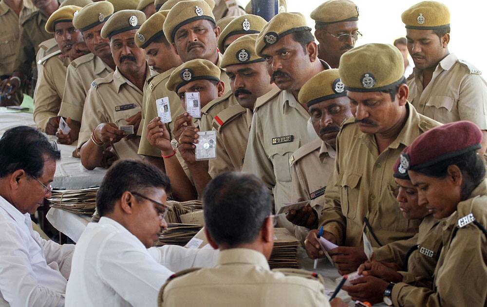 Home guards display their identity cards as they stand in a queue to cast their votes before heading off to their assigned polling stations, in Ahmadabad, India.