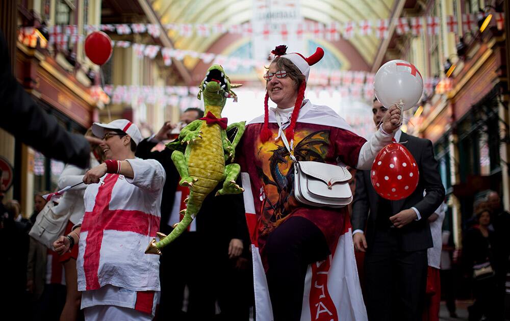 People wearing clothing with the cross of St George dance to music from a band performing on stage during an event to celebrate St George`s Day in Leadenhall Market in the City of London.