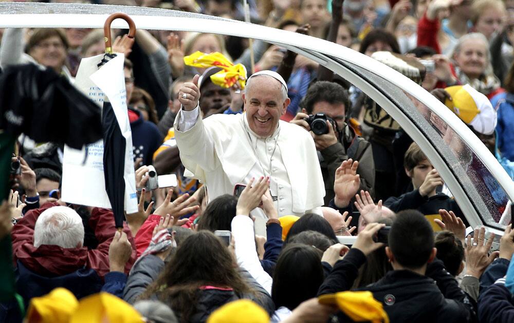 Pope Francis waves to faithful as he is driven through the crowd for his weekly general audience, in St. Peter`s Square, at the Vatican.