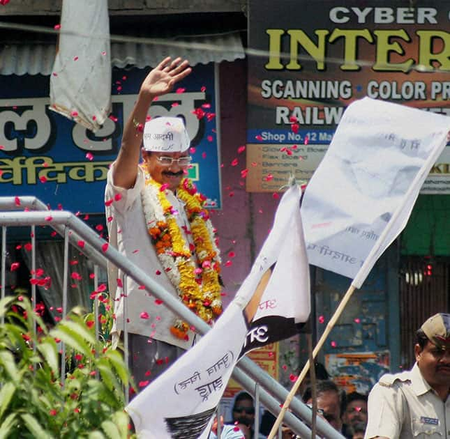 AAP convener Arvind Kejariwal waves to supporters at a roadshow before filing his nomination papers in Varansi.