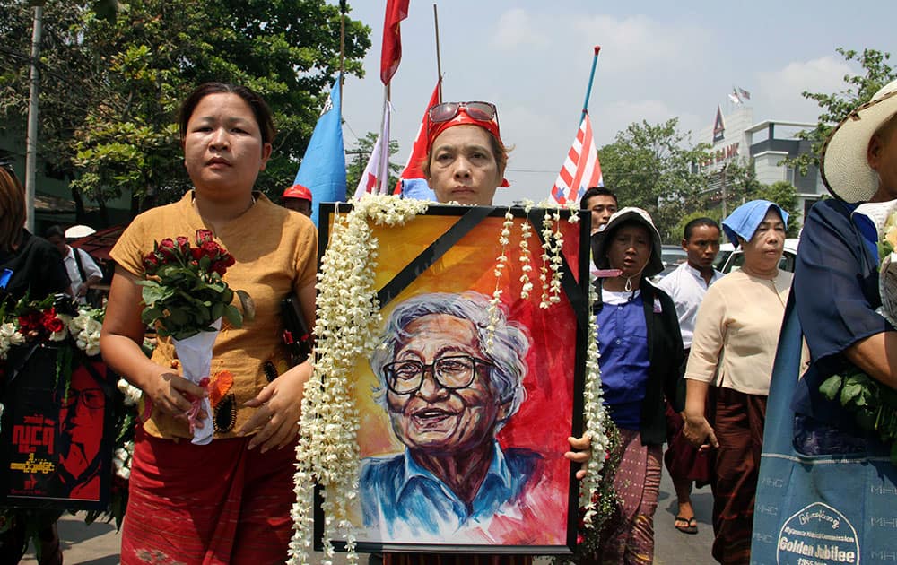 A member of Myanmar opposition leader Aung San Suu Kyi`s National League for Democracy (NLD) party carries a portrait of Win Tin, a senior leader of the party while marching with fellow NLD members to Ye-Way cemetery to attend the funeral of Win Tin in Yangon, Myanmar.