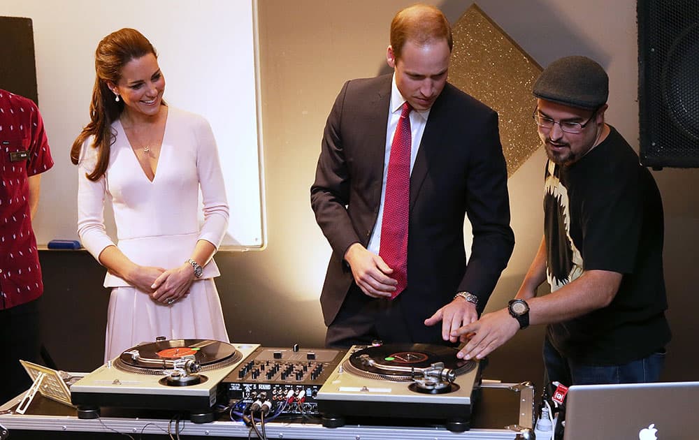 Britain`s Kate, the Duchess of Cambridge, watches as Prince William, center, uses the DJ decks at the youth community center, The Northern Sound System, in the suburb of Elizabeth, in Adelaide, Australia.