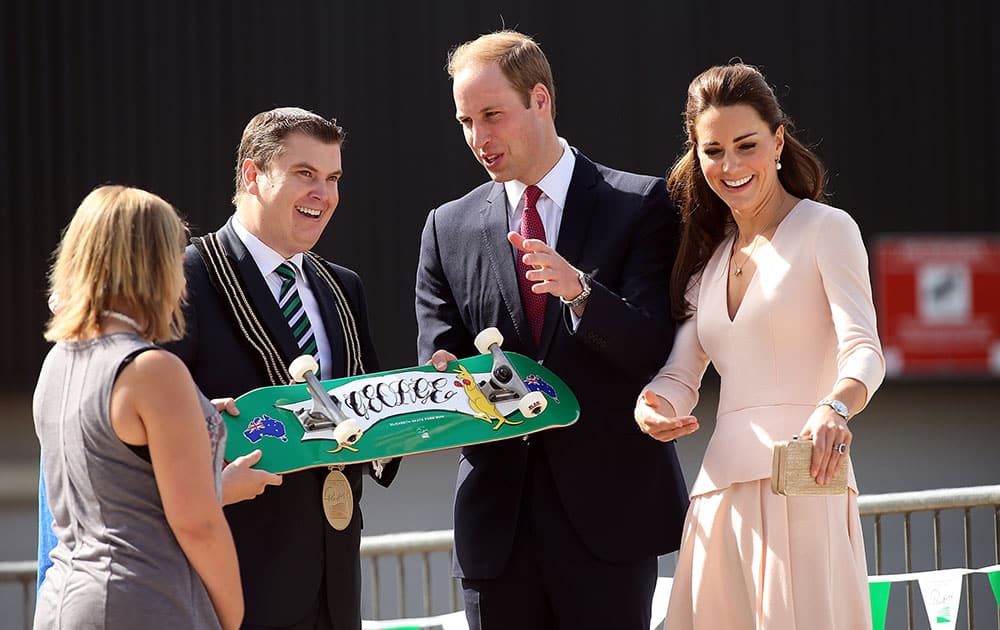 Britain`s Prince William, second right, and his wife Kate, the Duchess of Cambridge, right, are given a skateboard by the City of Playford Mayor, Glenn Docherty, second left, during a display at a skate park in the suburb of Elizabeth, in Adelaide, Australia.