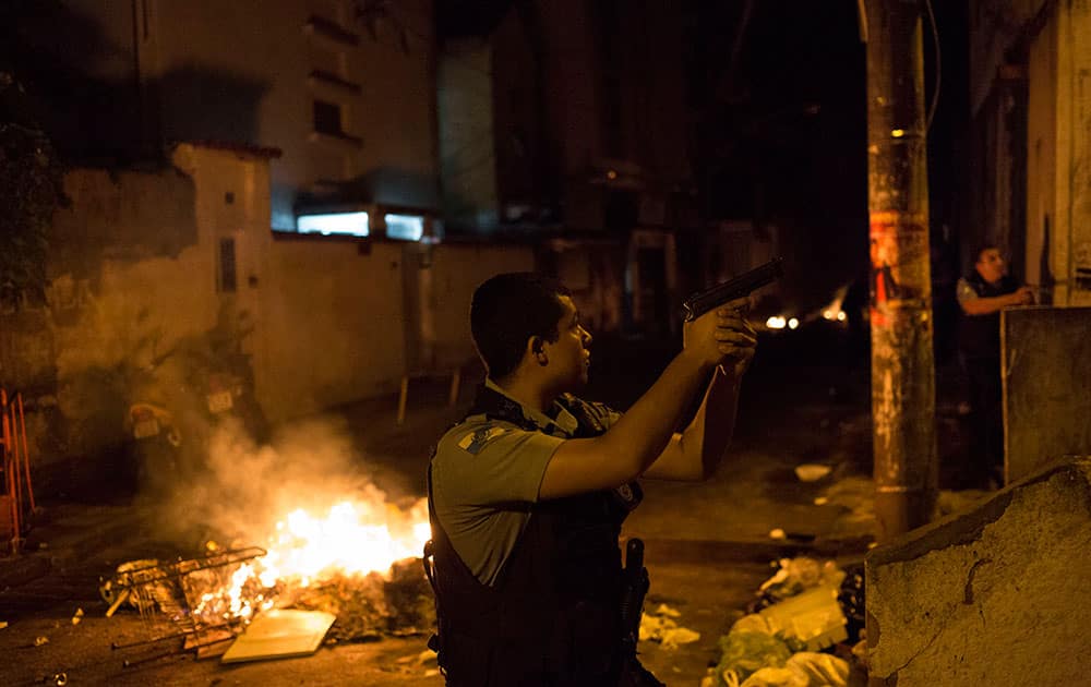 Officers of the Police Pacification Unit patrol next to a burning barricade during clashes at the Pavao Pavaozinho slum in Rio de Janeiro, Brazil.